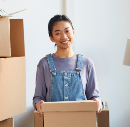 Smiling Asian Woman Holding Box In New House Vmrndzq.png